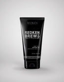 Black tube of Redken Brews hair product on a light gray background