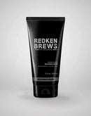 Black tube of Redken Brews molding paste on a light gray background