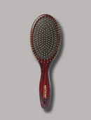 A HUSTAMO oval hairbrush with a dark reddish-brown wood grain handle and backplate, accented with gold-tone metal pins, shown against a solid gray background.