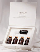 HISTEMO Ion-To G Forte hair treatment set in a white presentation box, containing four amber glass ampoules and one black spray bottle, displayed on a soft white fabric background.