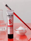 A tube of HistoTo Ion-To Hair & Scalp Science Specialist Scalp Cleanser stands on a glossy pink surface, with a red-handled brush behind it and a small glass bowl of white foam in front. The HistoTo brand name is visible on the tube and bowl.