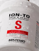 A close-up of a white plastic jar of Histemo Ion-To Hair & Scalp Science Specialist Active Factor Scalp Cleanser, covered in water droplets. The label features black text and a prominent red 'S' logo.